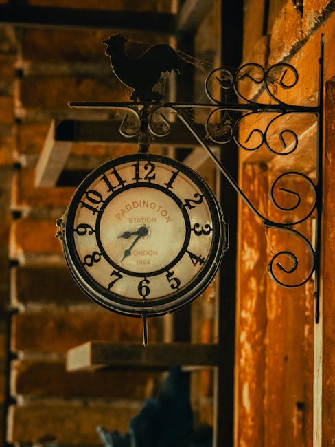 Close-up view of a large, vintage-style clock with Roman numerals and black clock hands, mounted on the exterior wall of a historic building near Paddington Station. The clock face is illuminated with